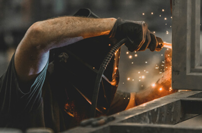 Welder working on a stainless steel project in an industrial space.
