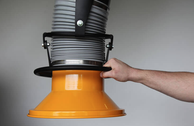 Welder with hand on fume extraction arm to position it for a work project.