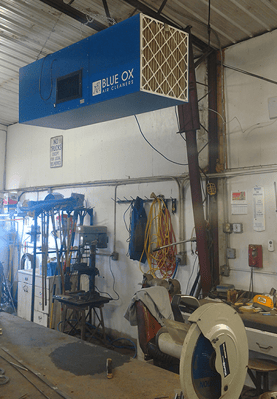 A small shop with ceiling-mounted OX3000 air cleaner removing dangerous welding fumes.