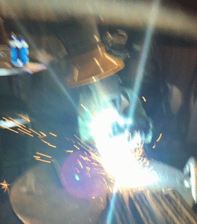 A welder working on a metalworking project and using a Fume Xtractors fume arm to extract smoke and fumes from above the source.