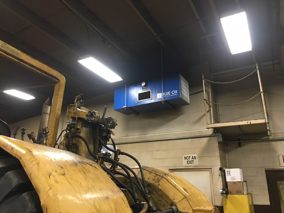 Ceiling-mounted OX3000 air cleaner over the welding area in a heavy equipment fabrication shop