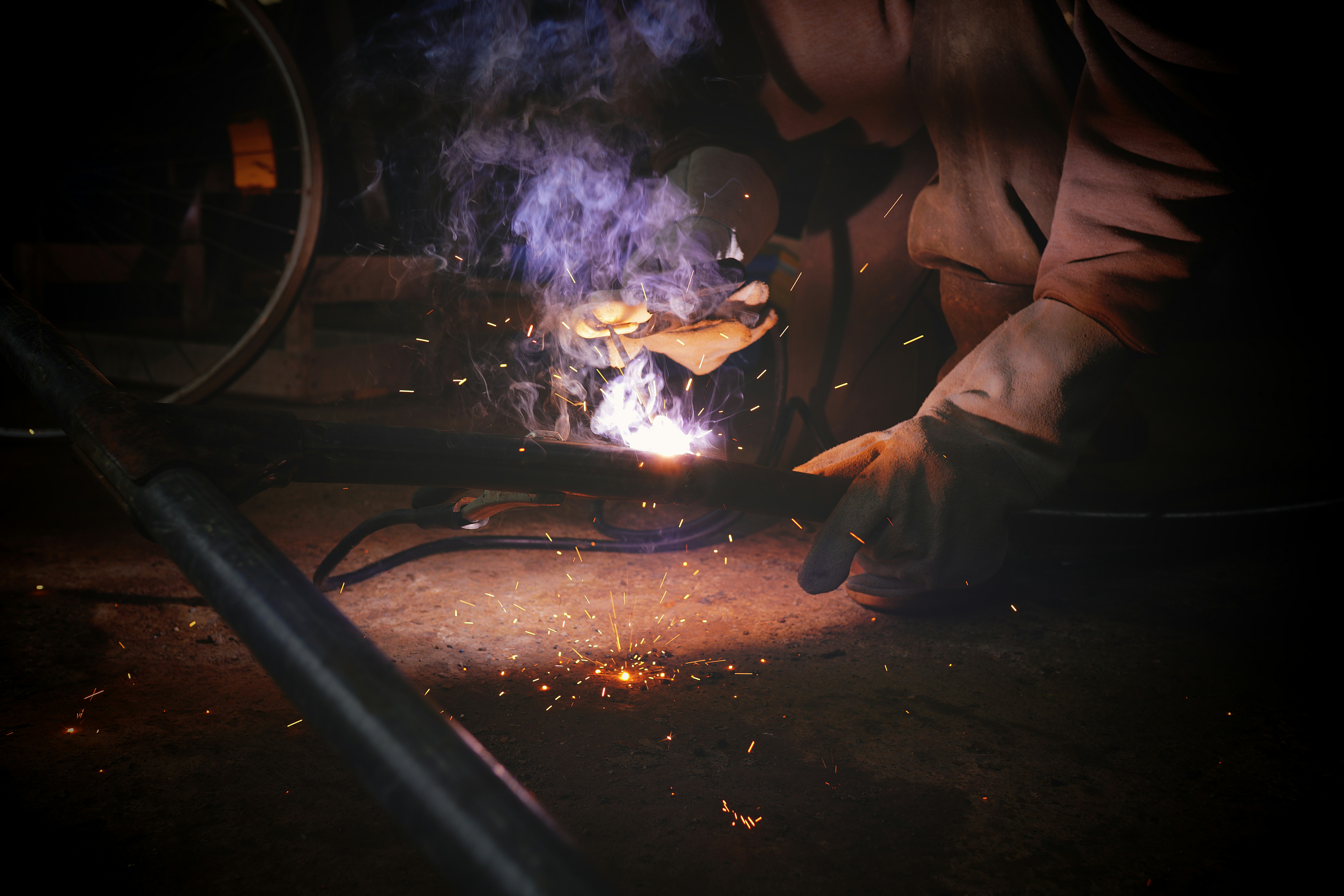 A welder working on a project that involved galvanized steel while fumes and sparks emit.